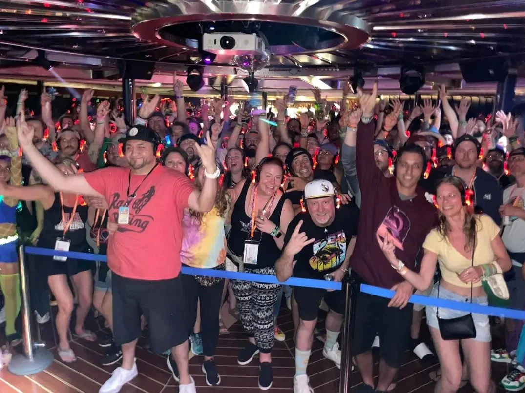 Silent-disco crowd with hands in the air and colorful headphones aboard the 311 Caribbean Cruise