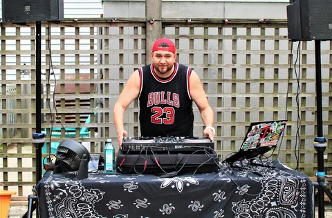CHIEF behind his full backyard DJ setup with speakers and a Rane controller